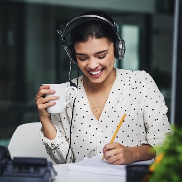 Smiling woman with headphones taking notes