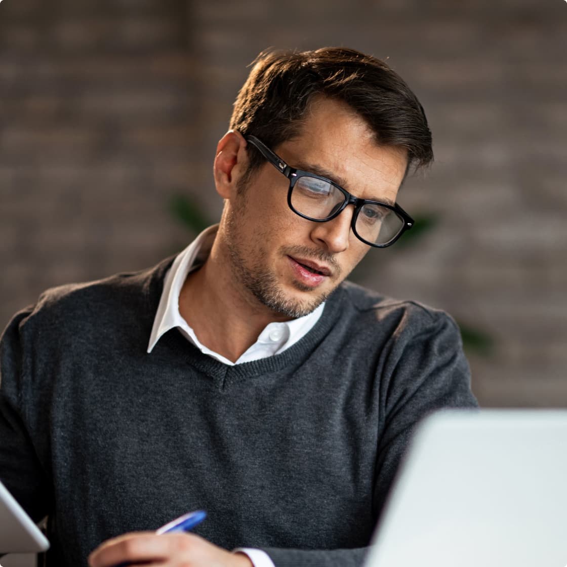 a guy taking notes with laptop in front