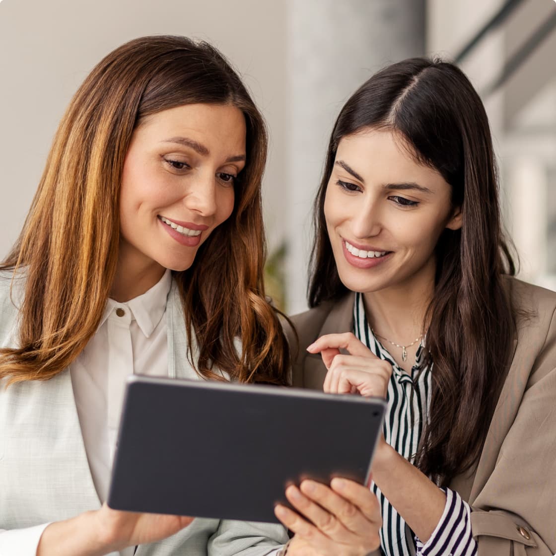 two women looking at a tablet in office