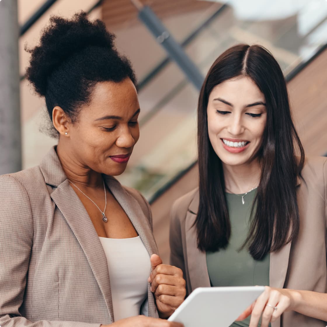 Two lady colleagues smiling and working at office