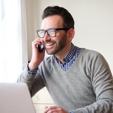 Man wearing grey sweater speaking over phone